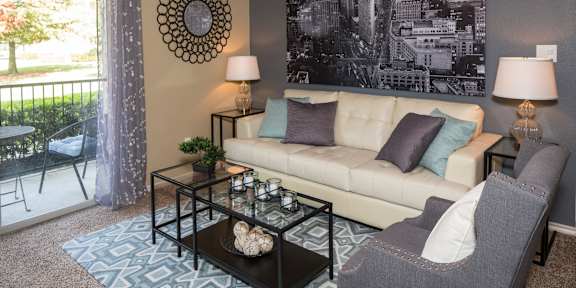 A living room with a couch, chair, and a large picture on the wall. at Infinity on Sunnyvale Apartments , Mesquite, 75150