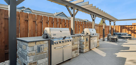A row of outdoor kitchen appliances are lined up under a pergola.