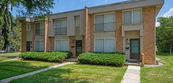 A brick apartment building with green bushes in front.