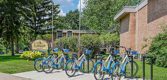 A row of blue bicycles are parked in front of a building.