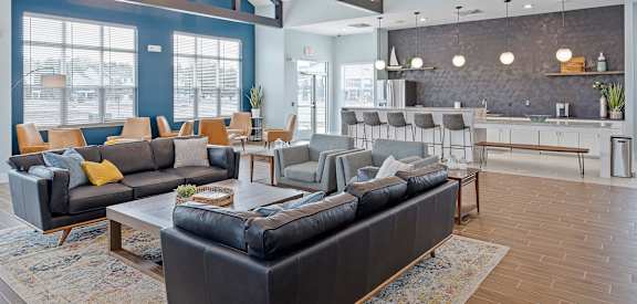 A modern living room with a black leather couch and wooden floors.