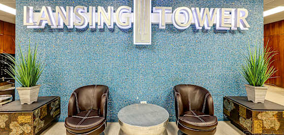 Two brown leather chairs are placed in front of a blue wall with the word "LANSING" written on it.