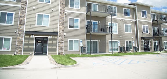 A large apartment complex with a parking lot in front.