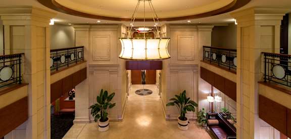 A large chandelier hangs from the ceiling in a grand hallway.