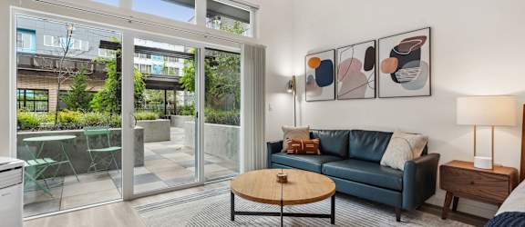 A living room with a couch, a coffee table, and a painting on the wall.