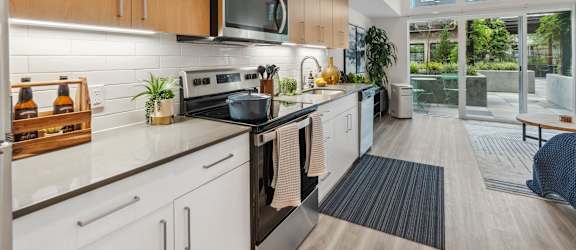 A modern kitchen with white cabinets and a black countertop.
