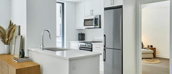 A modern kitchen with a white countertop and a refrigerator.