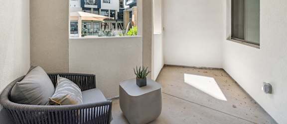 A patio with a couch and a table with a plant on it.