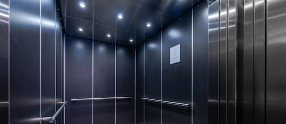 A stainless steel elevator with a white paper on the wall.