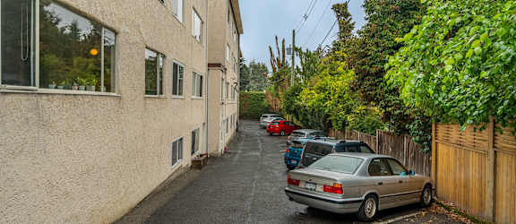 A car is parked on the side of a narrow street.
