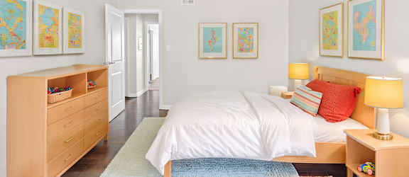 A bedroom with a bed, nightstand, and a dresser with a lamp on top.