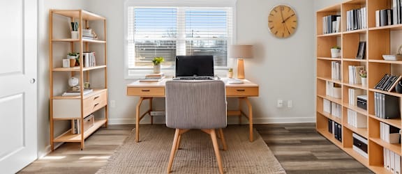 A room with a desk, chair, and bookshelves.