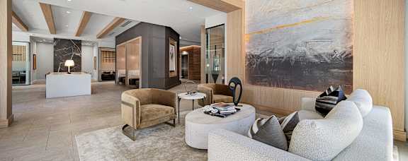 Stylish clubroom lounge with designer seating, wood accents, and walls of windows for gathering and relaxing