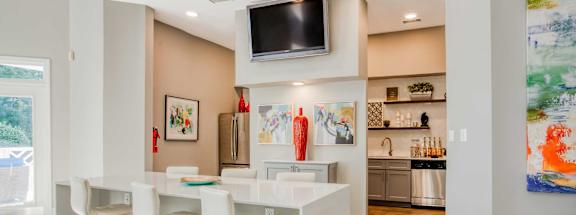 A modern kitchen with white bar stools and a white counter.