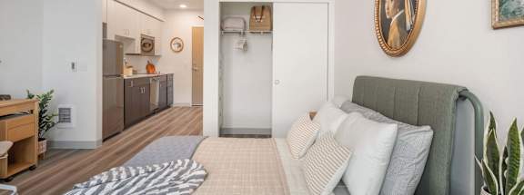 A bedroom with a bed, a couch, and a painting on the wall at Nook at Northaven Apartments, Seattle, WA
