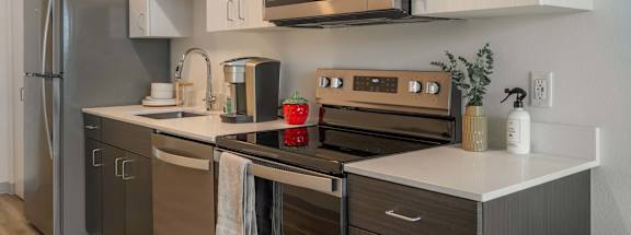 A modern kitchen with stainless steel appliances and white cabinets at Nook at Northaven Apartments, Seattle, Washington