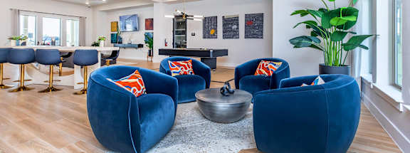 A living room with blue chairs and a wooden ceiling.