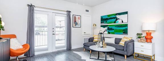 A living room with a grey couch, orange chair, and a painting on the wall.