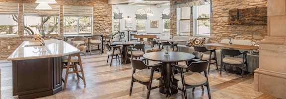 A modern dining room with a stone wall and a large island at The Villas at Ellis Manor, Fresno, CA