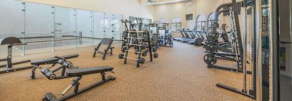 A spacious gym with a variety of equipment including treadmills, weights, and exercise machines at The Villas at Ellis Manor, Fresno, CA