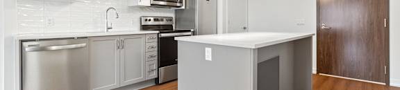 A kitchen with white cabinets and a wooden door.