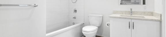 A white bathroom with a toilet, sink, and bathtub.
