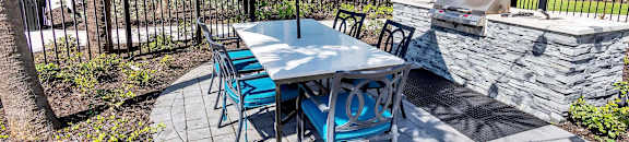 A patio with a table and chairs under a blue umbrella. at AVLI AT CROSSTOWN CENTER Apartments , TAMPA, FL, 33619
