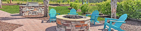 A fire pit surrounded by blue chairs and palm trees. at GRANDVIEW AT CLEAR POND Apartments , MYRTLE BEACH, SC, 29579