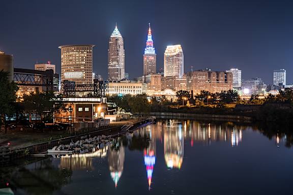 A city skyline at night with a reflection in the water.
