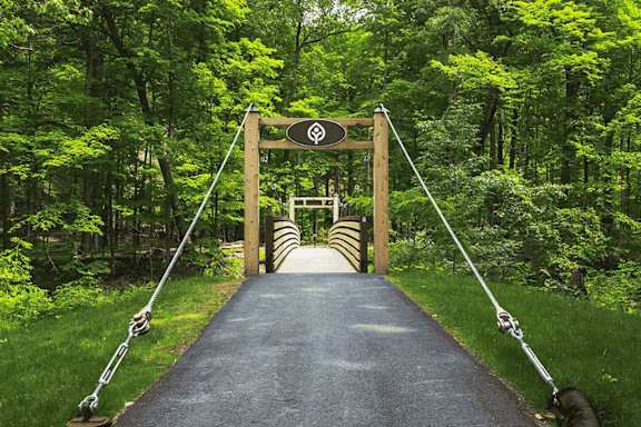 A wooden bridge with a sign on it in the middle of a forest.