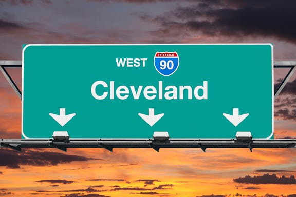 A highway sign for West 90 towards Cleveland with three downward arrows.