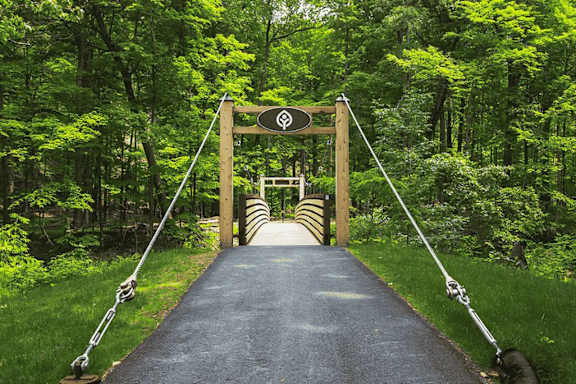 A wooden bridge with a sign on it in the middle of a forest.