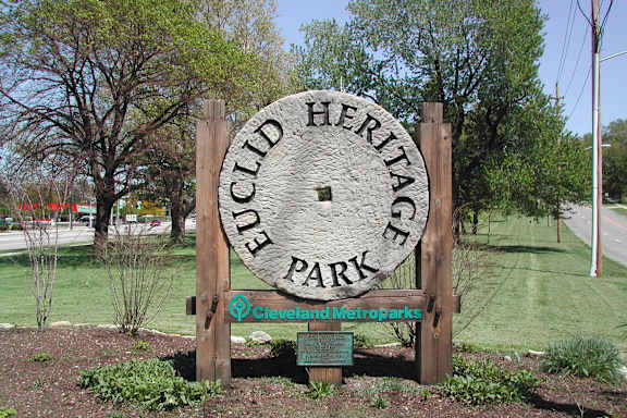 A sign forCLCID HERITAGE PARK is in front of a grassy area.