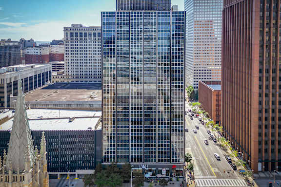 A tall glass building stands in the middle of a city street.
