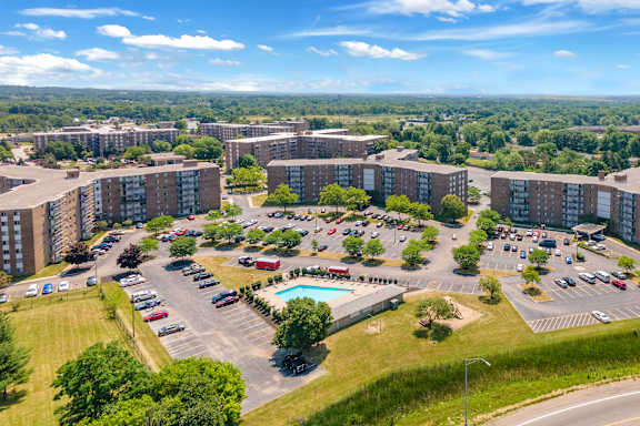 A large apartment complex with a parking lot and a pool.