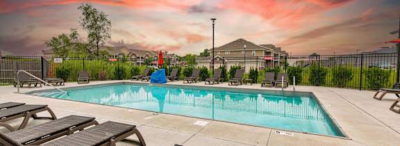 A pool surrounded by a fence and chairs. at Lake Shore Apartments, Ankeny, IA