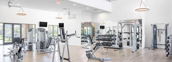 A spacious gym with a variety of equipment and a balcony overlooking the workout area.