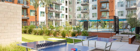 A ping pong table is in the middle of a courtyard with buildings in the background.