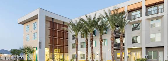 A modern building with palm trees in front.