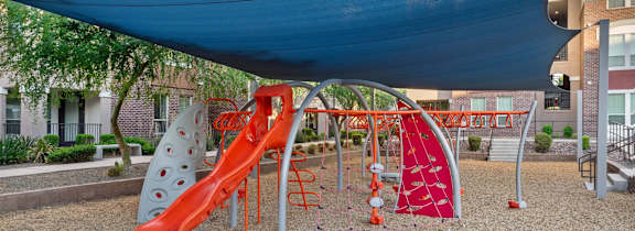 A playground with a red slide and a blue canopy.