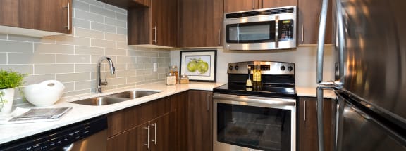 a kitchen with stainless steel appliances and wooden cabinets at Apartments at Denver Place, Colorado, 80202