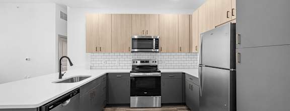 A modern kitchen with stainless steel appliances and wooden cabinets.