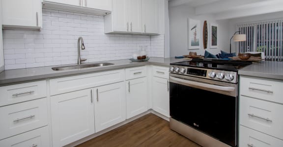 a kitchen with white cabinets and a stove and a sink at MALA GROVE Apartments, Hawaii, 96797
