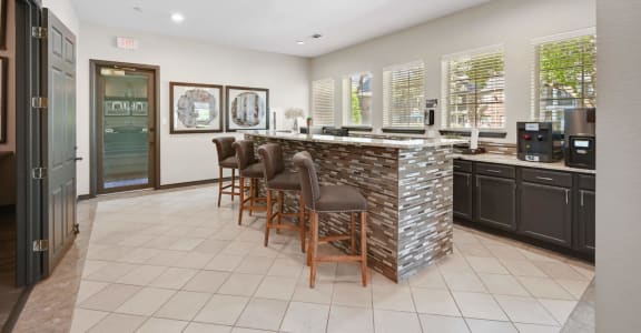 a kitchen with a counter and chairs in front of a bar