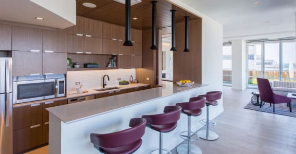a kitchen with wooden cabinetry and a long island with purple stools
