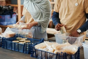 two people standing at a table with crates of food