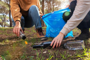 a person picking up a bottle of water from the ground