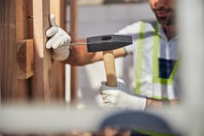 a man hammering a nail into a wooden wall with a hammer and a nail