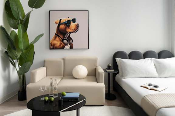 A living room with a couch, a coffee table, and a painting of a dog wearing sunglasses.