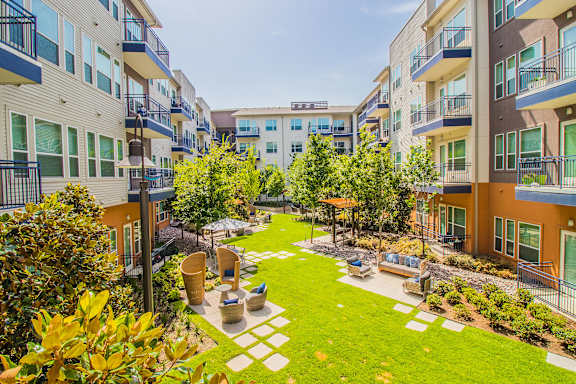 an apartment courtyard with grass and trees in the middle of it at South Side Flats in Dallas, TX